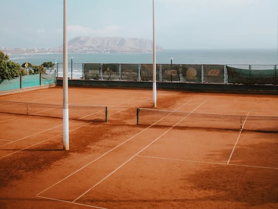 Pista de tenis de arcilla junto al mar con vistas a la montaña